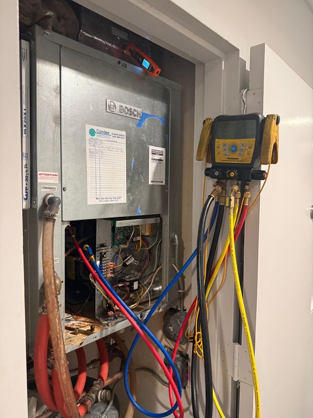 HVAC unit being serviced. Gauges and hoses connected to the unit in a closet.