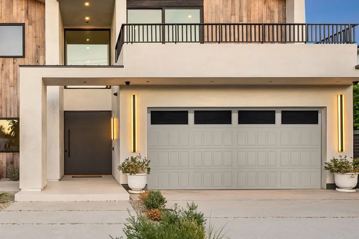 Modern two-story house exterior featuring a beige stucco garage, vertical wall lights, and a dark front door.