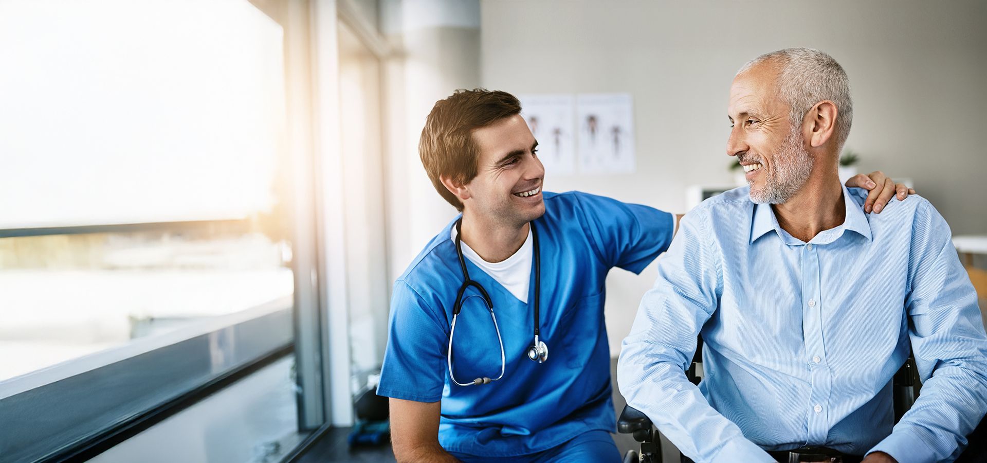 A nurse is talking to an older man in a wheelchair.