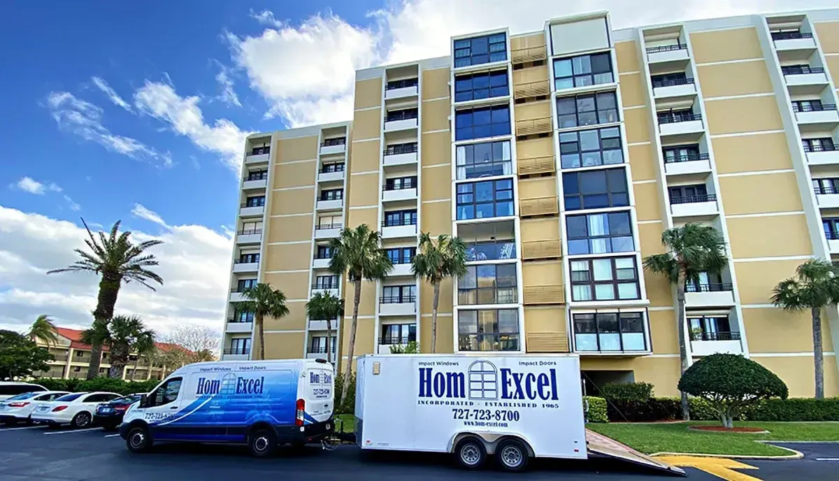 Moving truck parked outside a beige high-rise condo under a blue sky with palm trees