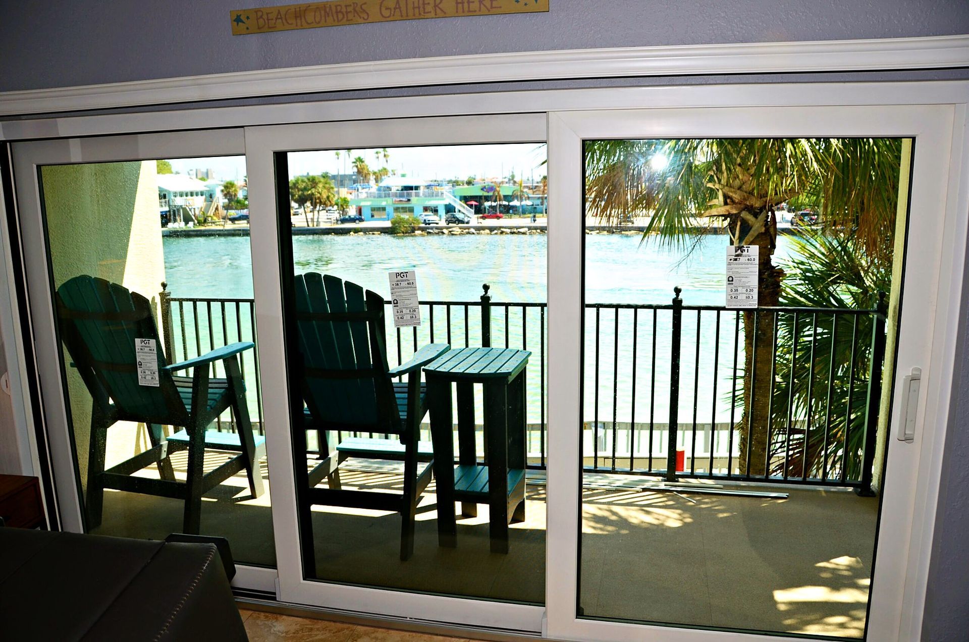 Patio with two green chairs and a small table by sliding glass doors overlooking water and trees