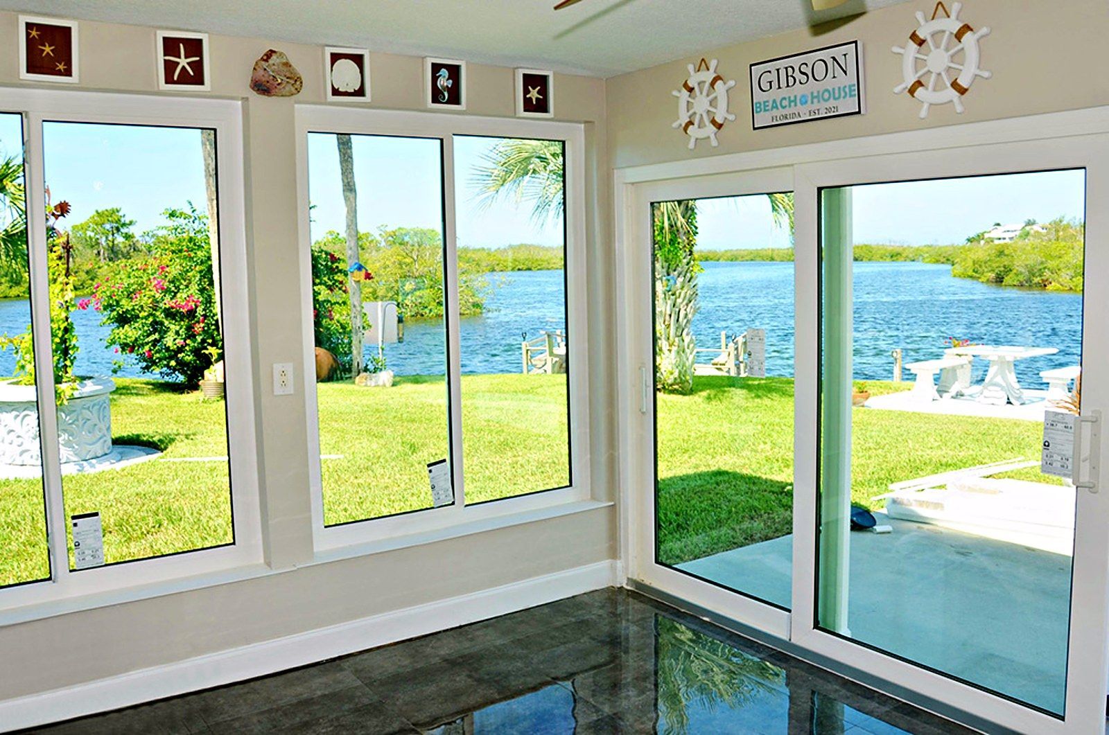 Bright room with large windows and sliding door opening to a sunny lakefront patio and lawn