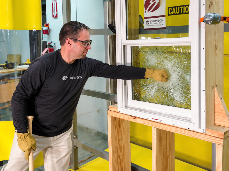 Worker in safety gloves breaking glass in a window test frame at a lab facility