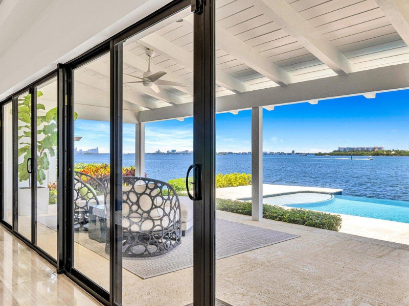 Modern patio with sliding glass doors, white pergola, pool, and ocean view