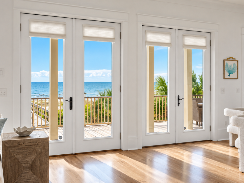 Bright living room with French doors opening to a sunny ocean view