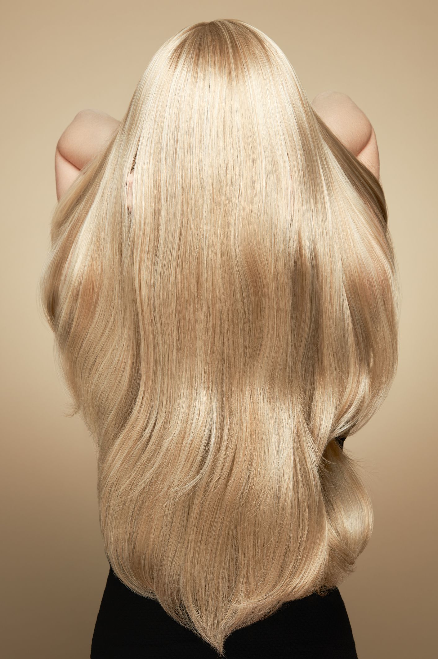 Blonde hair hanging down the back against a beige background