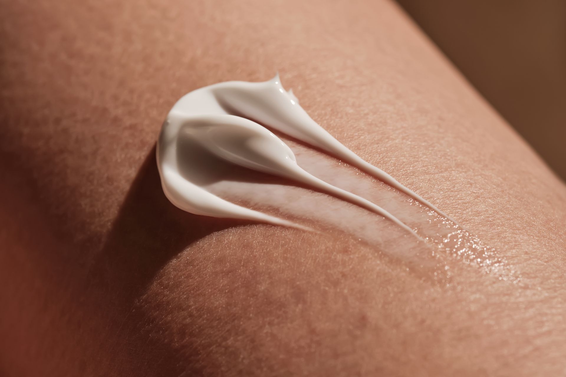 A dollop of white cream spread across a patch of human skin.