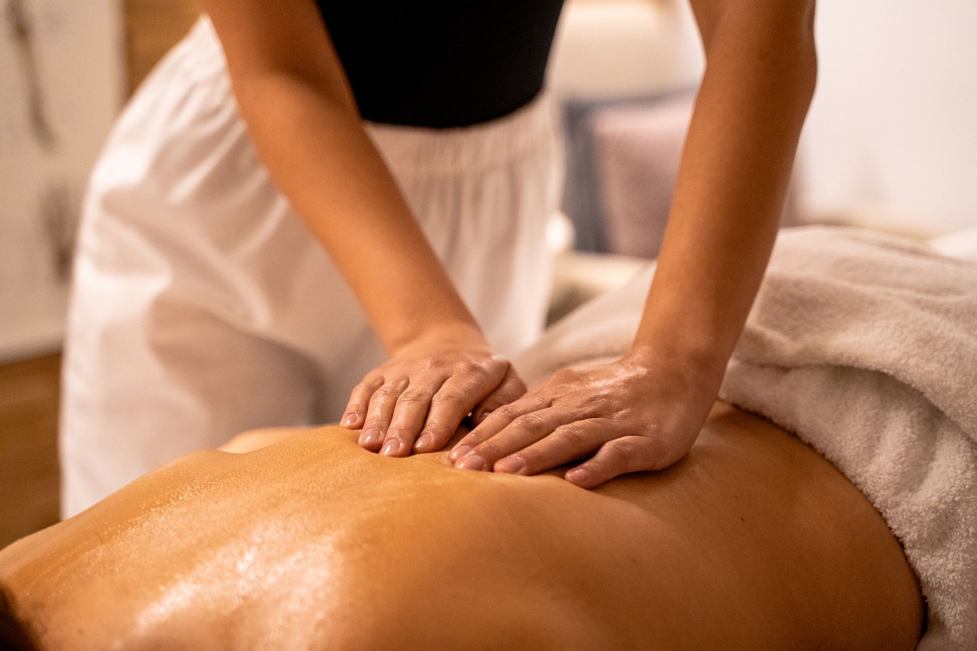 A therapist performs a professional back massage on a client lying on a treatment table.