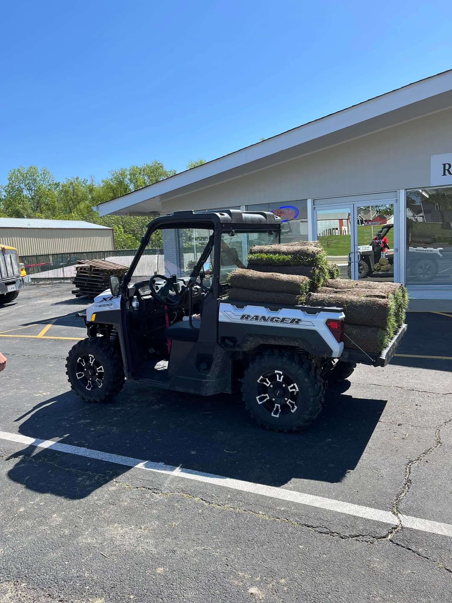 Black golf cart parked outside a building under a clear blue sky.