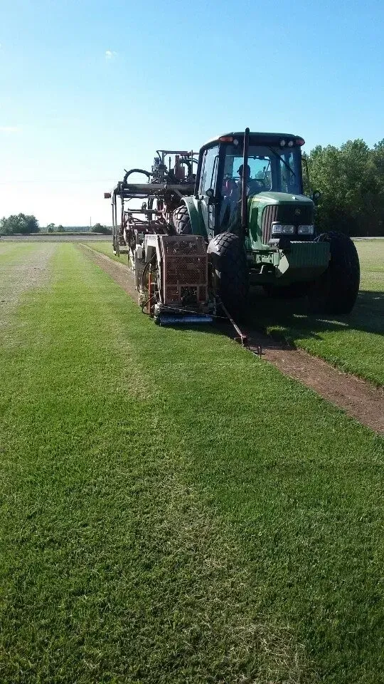 Large tractor spraying a grassy field on a sunny day