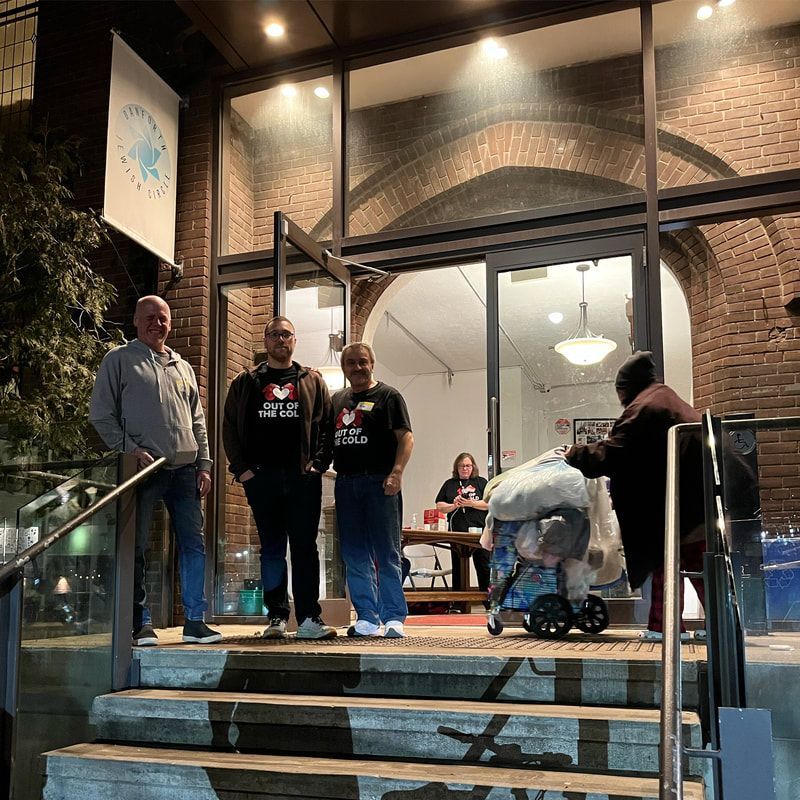 People standing on steps outside a brick building with glass doors at night