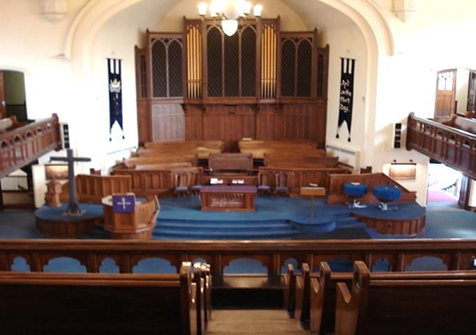 Church sanctuary with wooden pulpit, blue-clothed lectern, and rows of empty pews at the front