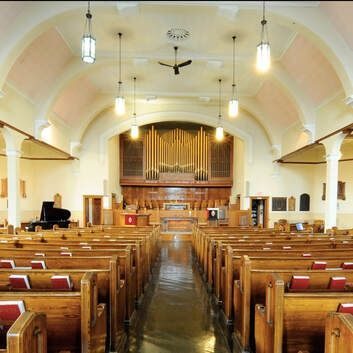 Interior of a church sanctuary with wooden pews and a large pipe organ at the front