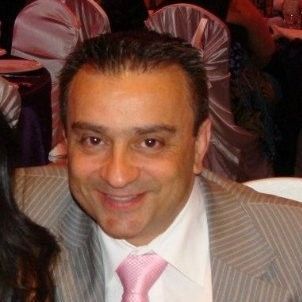Smiling man in a gray pinstripe suit and pink tie at an event