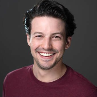 Smiling person in a maroon shirt against a dark gray background