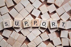 Wooden letter tiles spelling “SUPPORT” over scattered wooden blocks