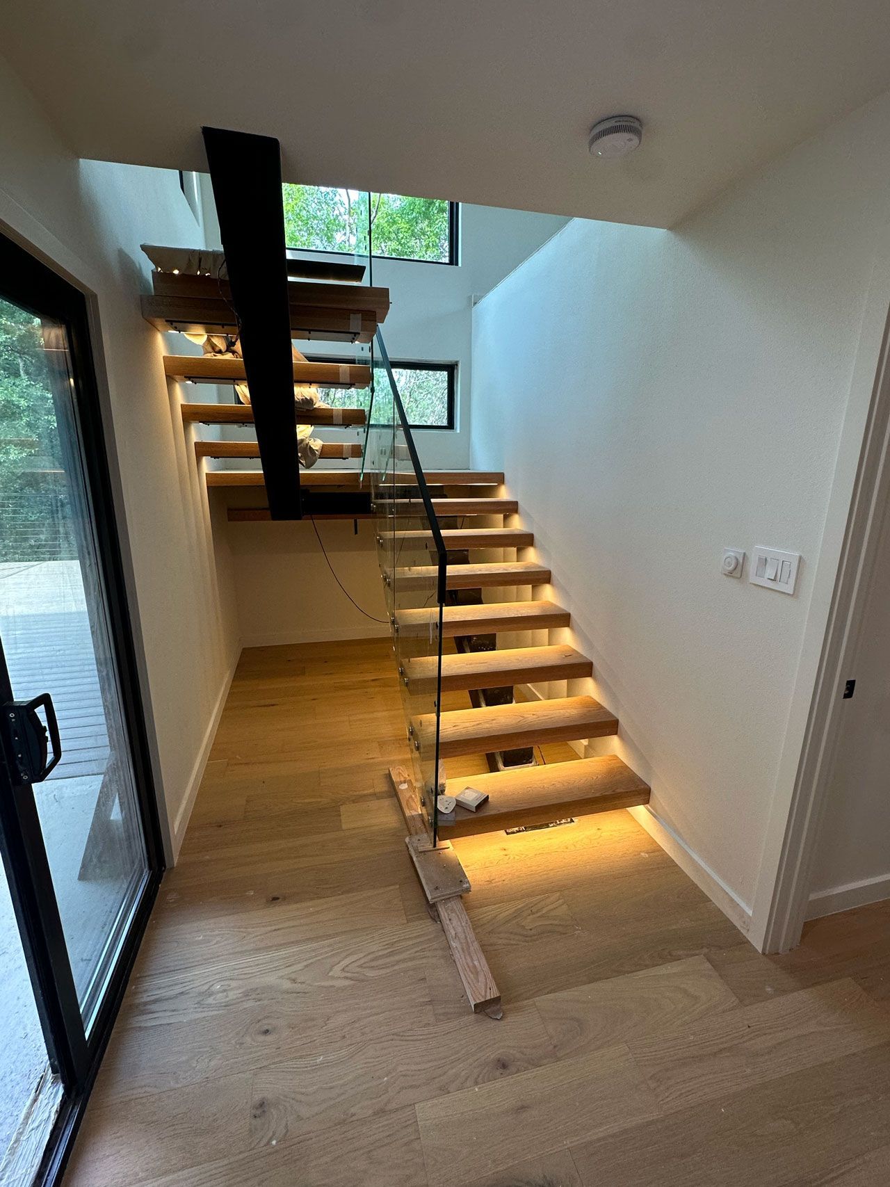 A wooden staircase with a glass railing in a hallway.