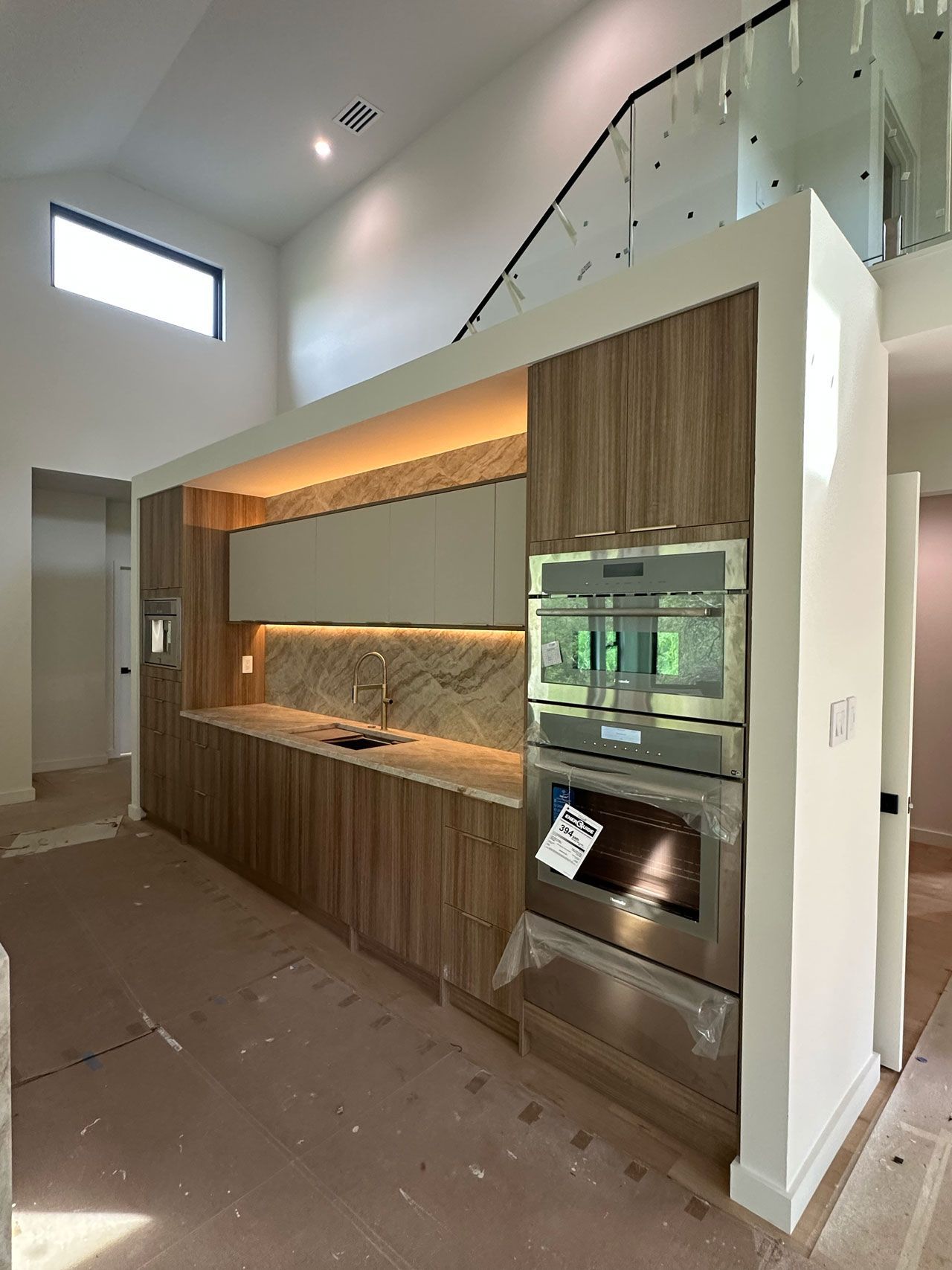 A kitchen with wooden cabinets and stainless steel appliances in a house under construction.