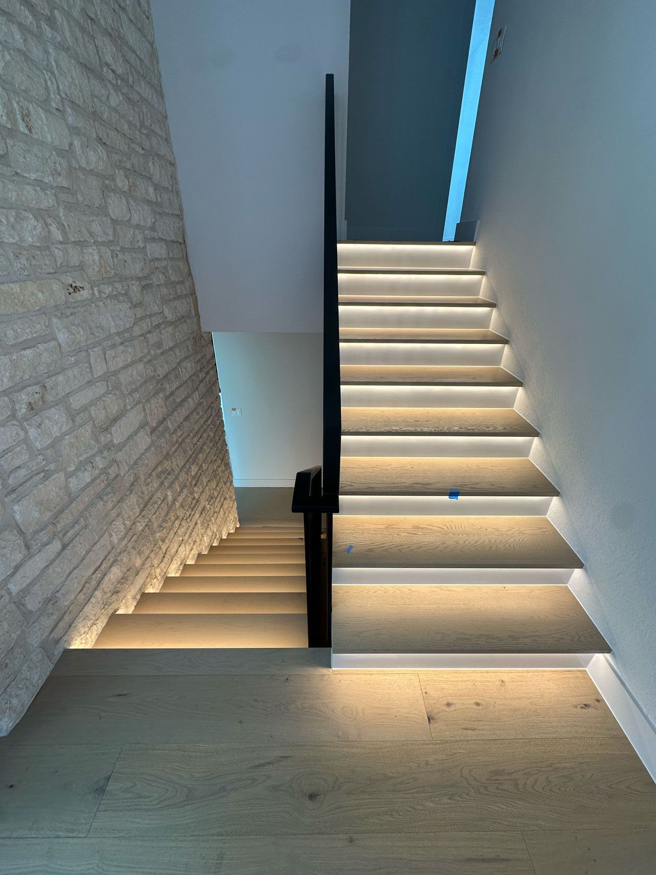 A staircase with lights on the steps and a brick wall.