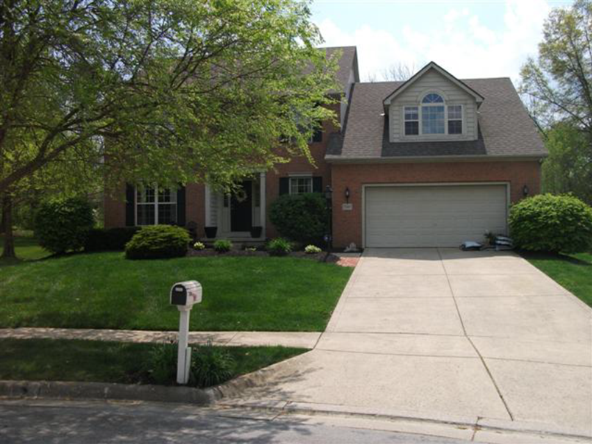A brick house with a white garage door and a mailbox in front of it