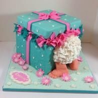 Turquoise and pink decorated cake with flower accents and a frilly skirt-like design on a baseboard