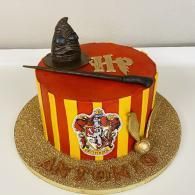 Red and yellow striped Gryffindor cake with Hogwarts crest and Sorting Hat topper