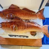 Two brown fish displayed on a white foam tray, likely for sale or serving.