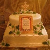 Two-tier white cake with green flowers and a framed orange plaque on top and front