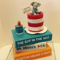 Stacked Dr. Seuss books topped with the Cat in the Hat and a small fish bowl centerpiece