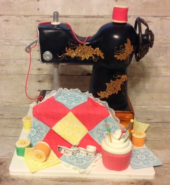 Vintage black sewing machine decorated with gold accents, surrounded by colorful quilt pieces and sewing notions