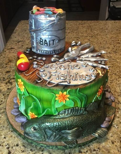 Fishing-themed decorated cake with silver bait bucket, fish, red bobber, and green water design