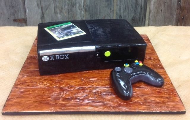 Black Xbox console with controller on a wooden board, against a rustic wood background