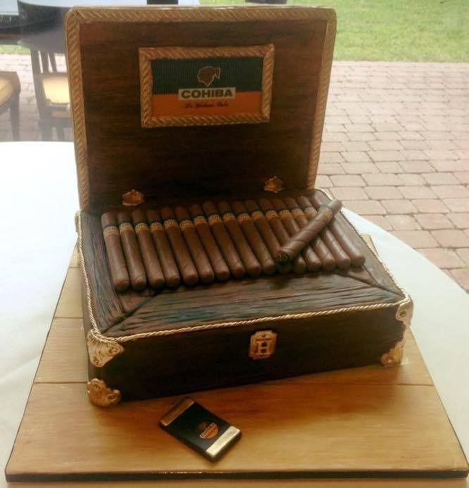 Open cigar box with cigars on a wooden table, outdoors on a patio.