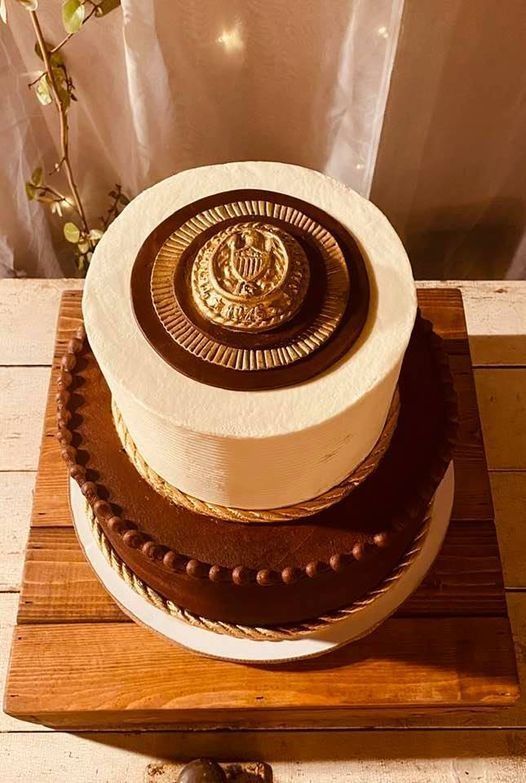 Two-tiered chocolate and cream cake on a wooden stand with a decorative chocolate top medallion