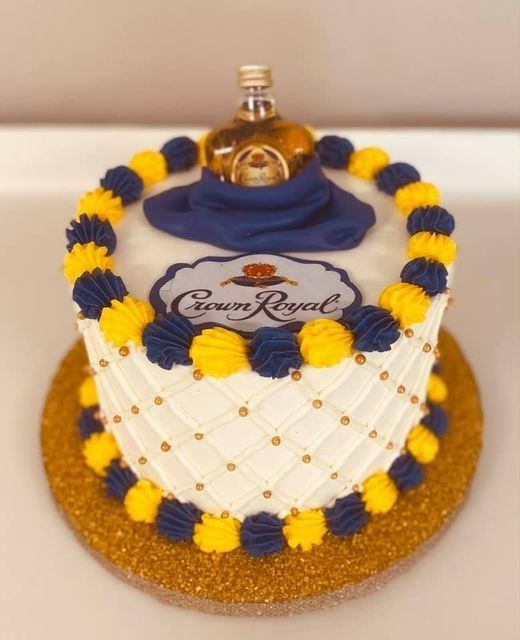 Decorated cake with blue, yellow, and white frosting topped with a small Crown Royal bottle