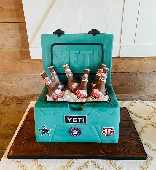 Teal YETI cooler cake with beer bottles and Texas A&M decorations on a wooden board