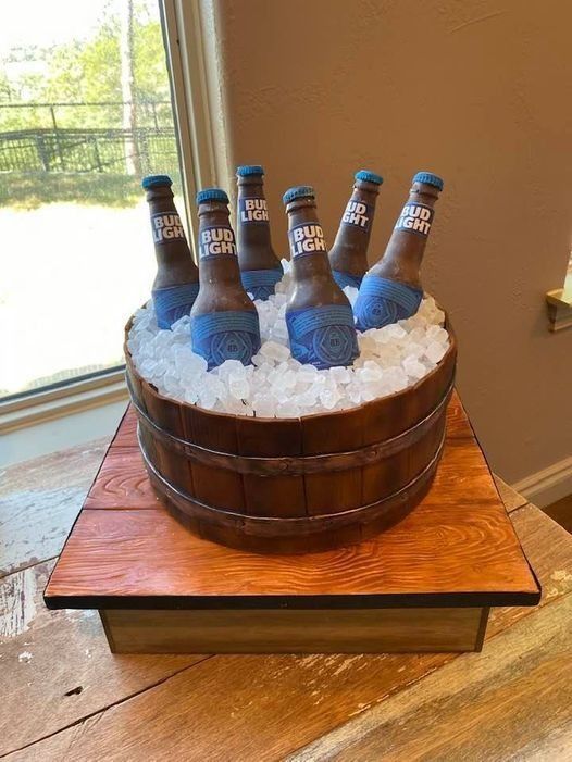 Beer bottles in an ice-filled wooden tub on a table by a window.