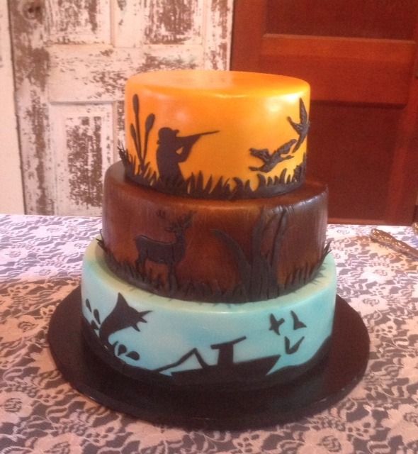 Three-tier Halloween cake with orange, brown, and blue sections and spooky silhouette decorations