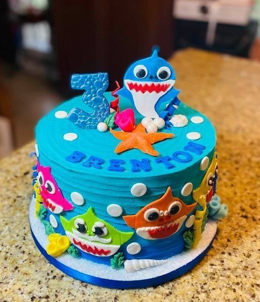 Blue Baby Shark birthday cake with colorful shark toppers and number 3 on top.