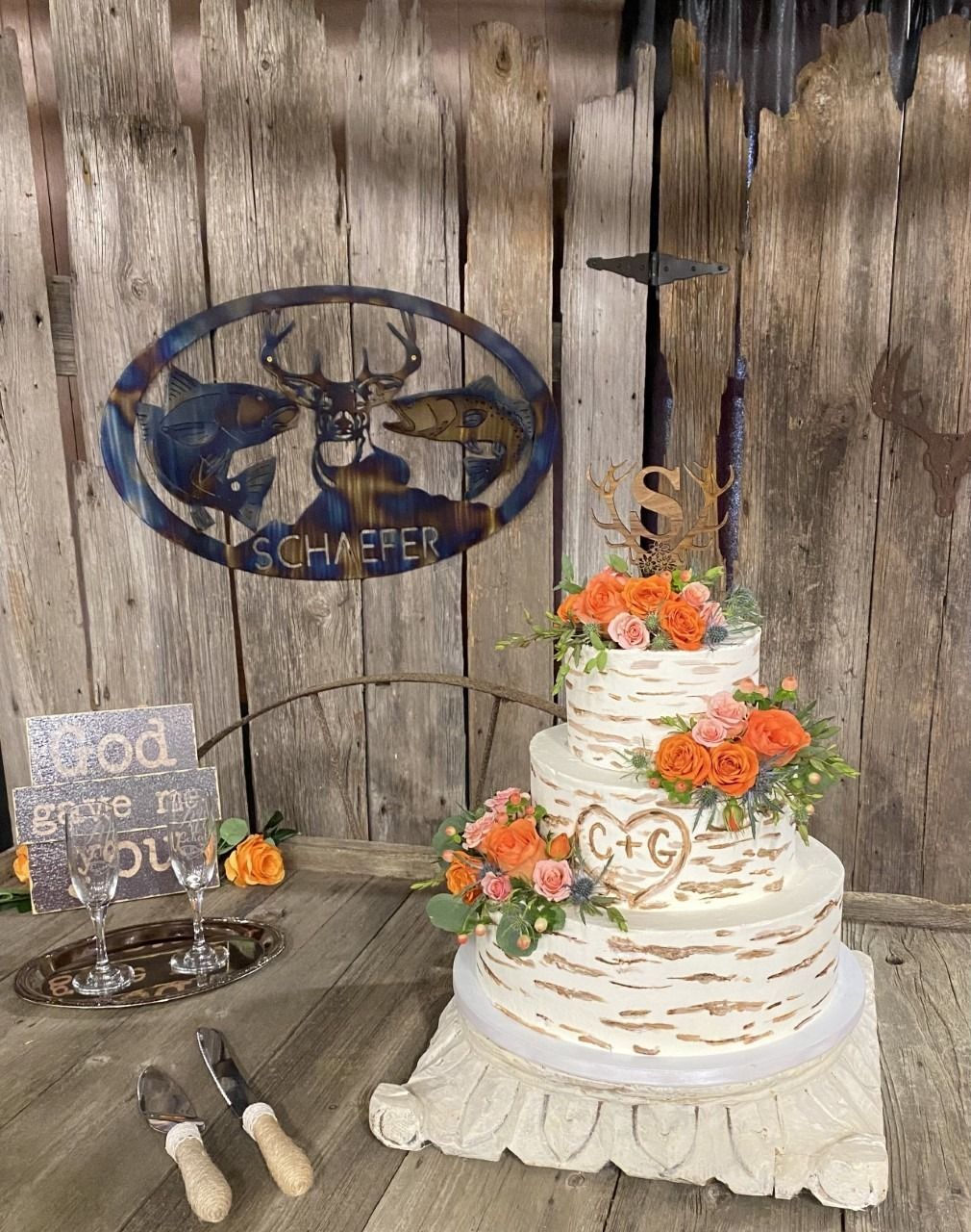 Rustic wedding cake with orange flowers on a table against a weathered wooden wall