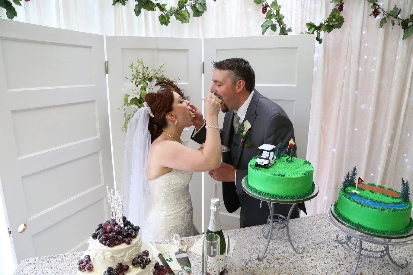 Bride and groom feed each other cake at a wedding reception with green frosted cakes nearby