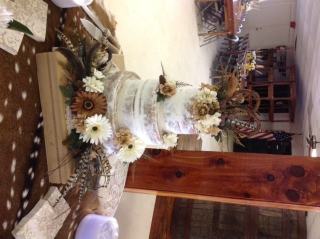 White tiered wedding cake on a decorated table with sunflowers and autumn accents indoors