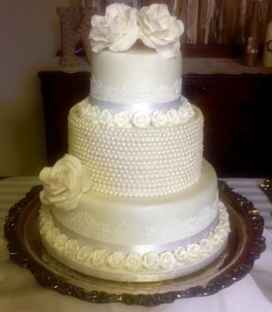 Elegant four-tier white wedding cake with floral decorations on a silver tray