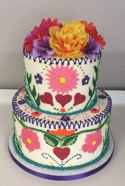 Colorful two-tier cake decorated with flowers and hearts on a white plate