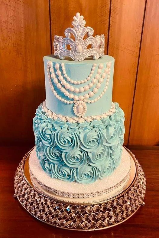 Three-tiered aqua and white decorated cake with pearl garlands on a silver stand