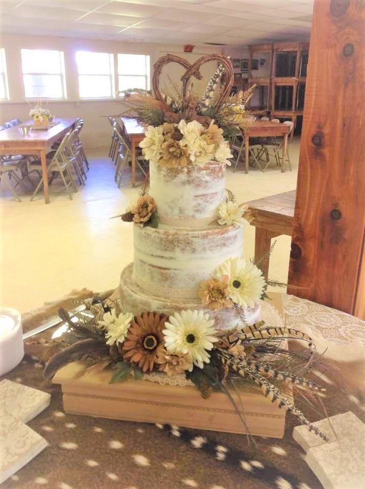 Floral tiered cake centerpiece with sunflowers and lace in a rustic dining room