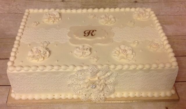 Decorated white rectangular cake with floral piping and a monogram on top