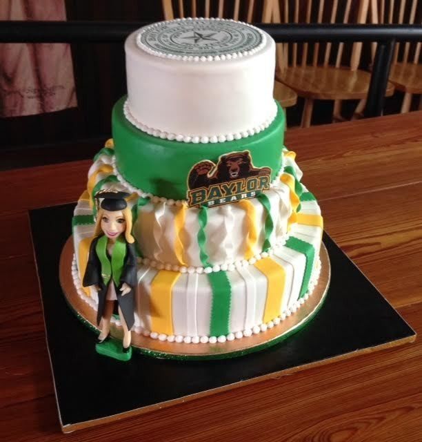 Green and white Baylor-themed layered cake with a topper and figure on a black board