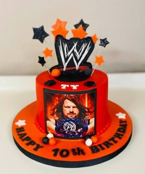 Orange WWE birthday cake with stars, wrestler topper, and “Happy 10th Birthday” on the base