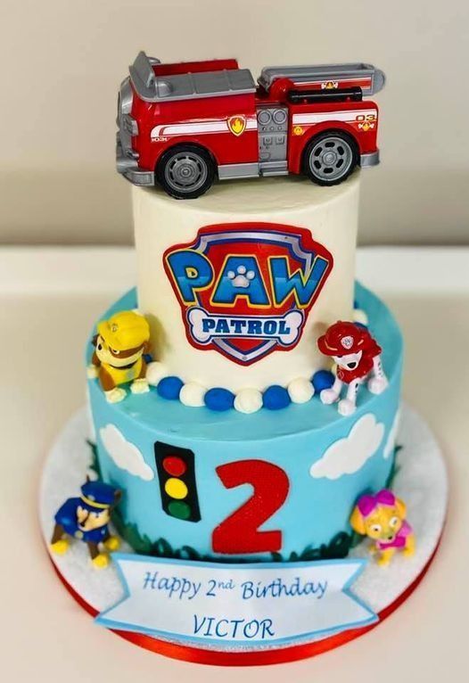 PAW Patrol birthday cake with red fire truck topper, paw badges, a red number 2, and the name Victor